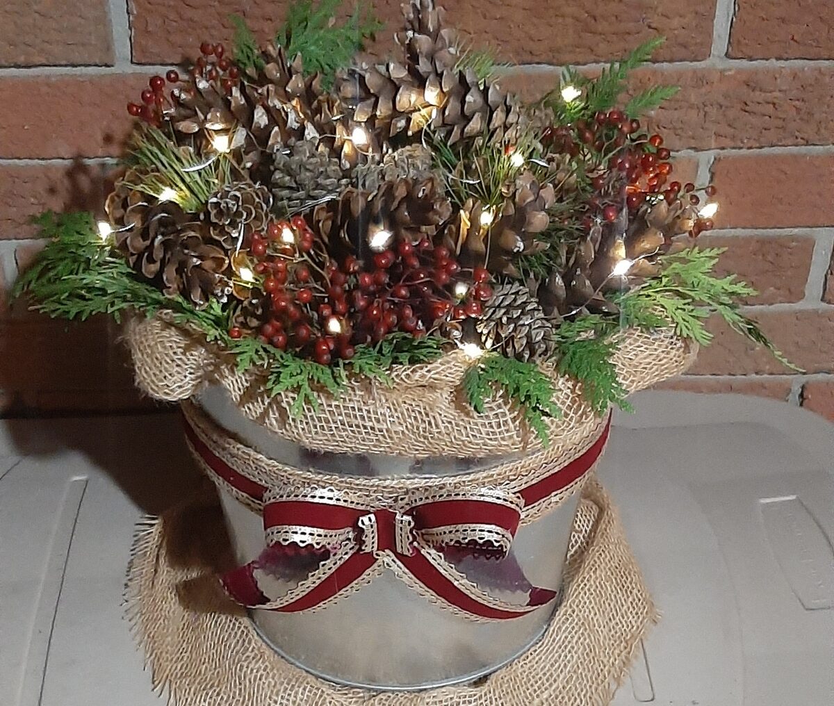 Fairy lights added to evergreens and pine cones in galvanized bucket