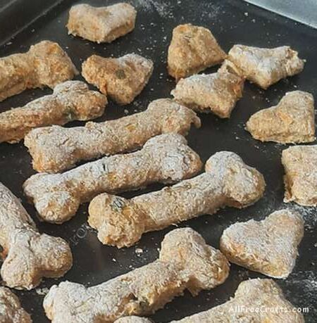 bone-shaped and heart-shaped dog cookies on a cookie sheet